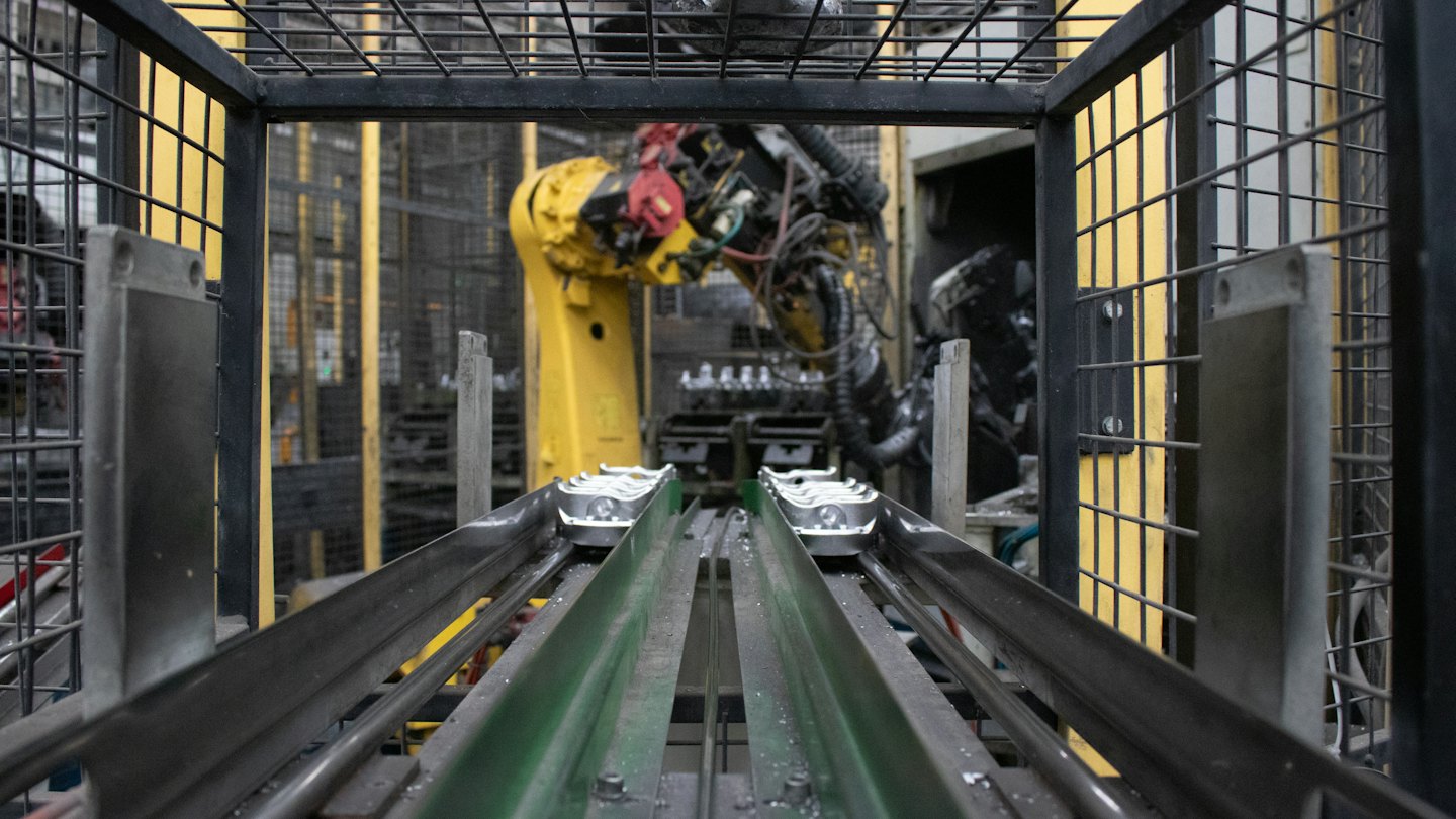 Ramię robota pracuje na linii produkcyjnej z przenośnikami taśmowymi.